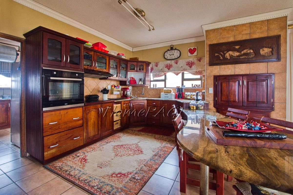 A traditional kitchen featuring dark wood cabinetry, granite countertops, a built-in oven, and tiled flooring with a breakfast bar area.