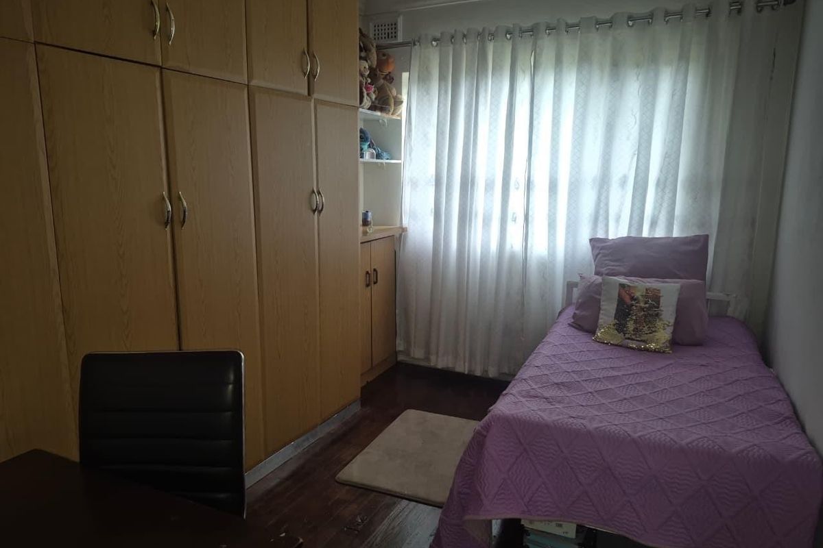 A functional bedroom featuring extensive built-in wooden cabinetry and laminate flooring, providing ample storage space.