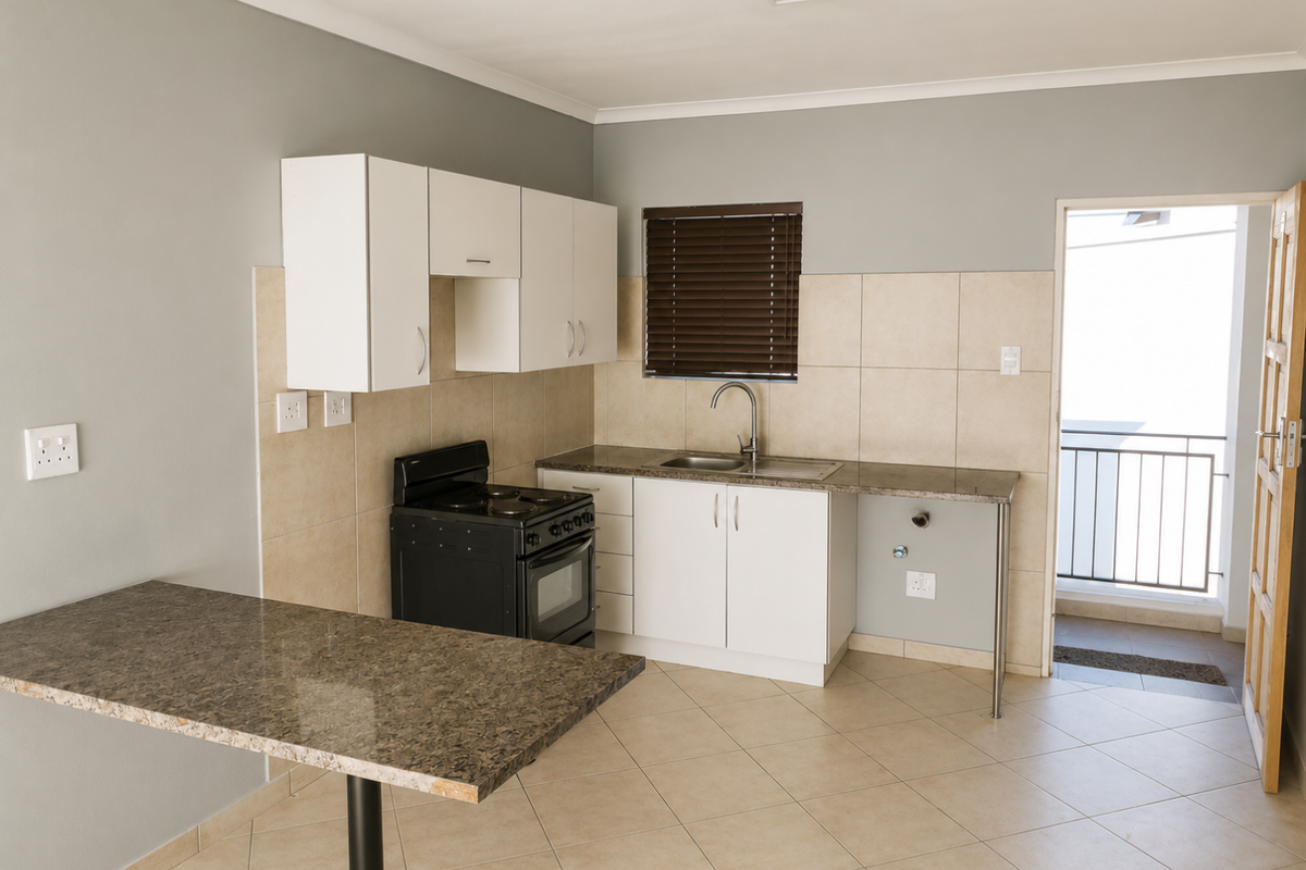 A clean, functional kitchen featuring granite countertops, white cabinetry, a freestanding stove, and tiled flooring, with direct access to an outdoor balcony.