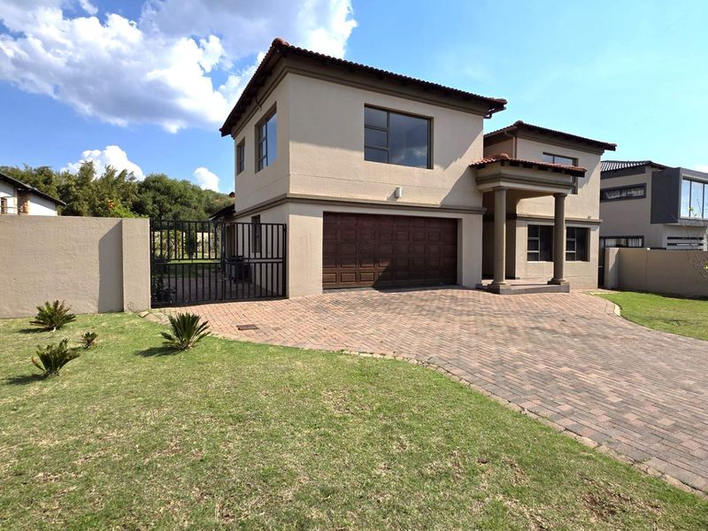 Front view of a two-story residential house featuring a paved driveway, double garage, and a covered entrance porch with columns.