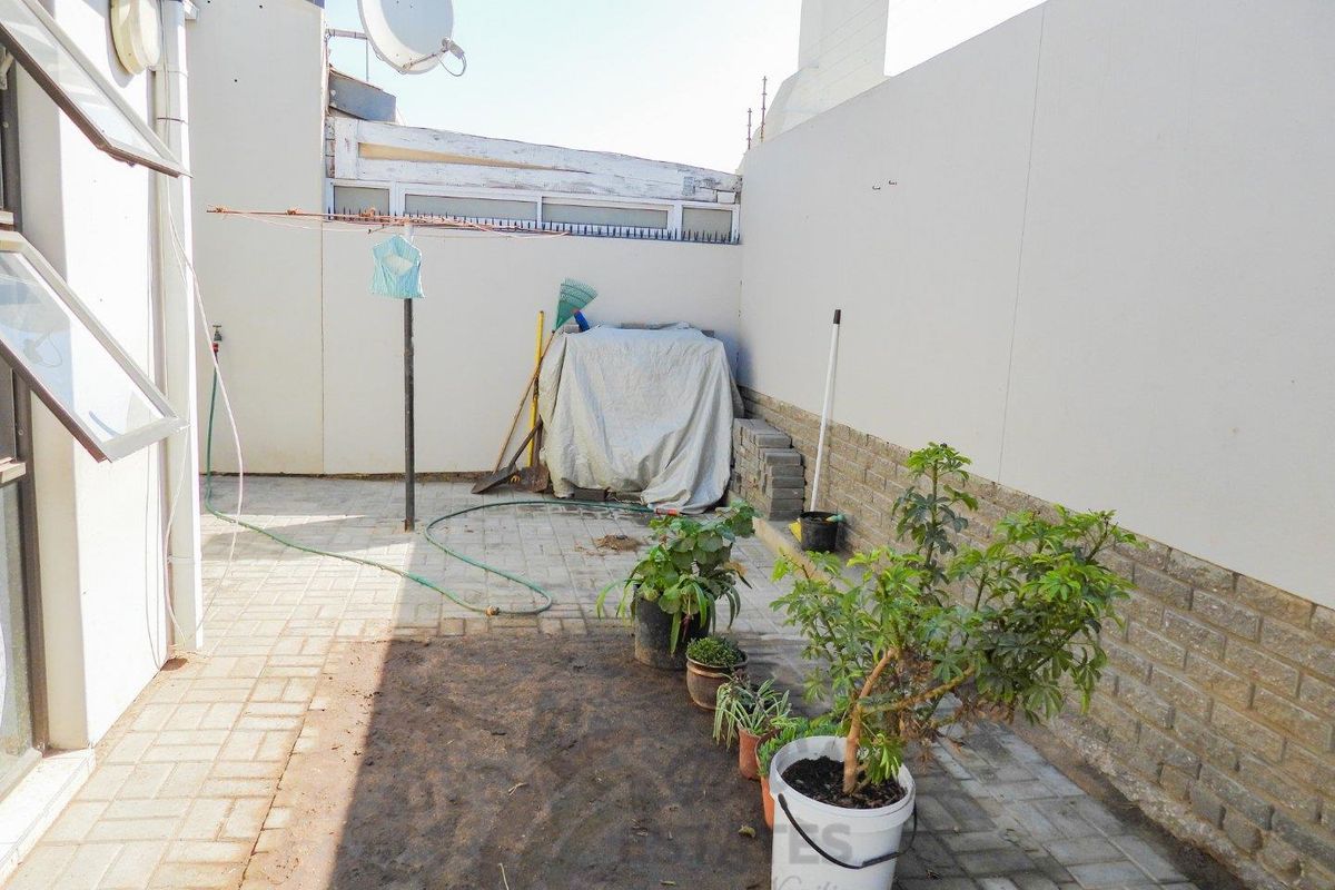 A paved rear courtyard area featuring high boundary walls, a satellite dish, and a clothesline, offering a private outdoor utility space.