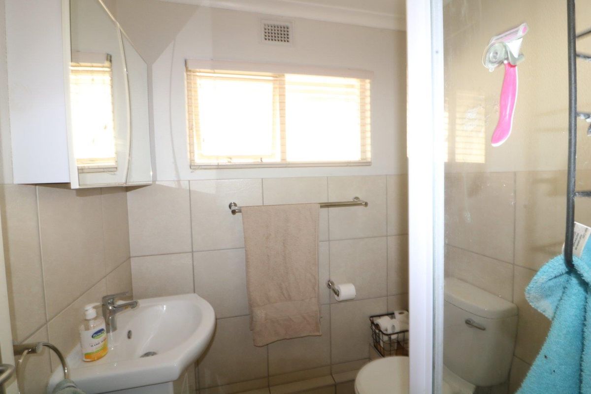 A functional bathroom featuring a pedestal basin, toilet, and shower enclosure with tiled walls and a medicine cabinet.