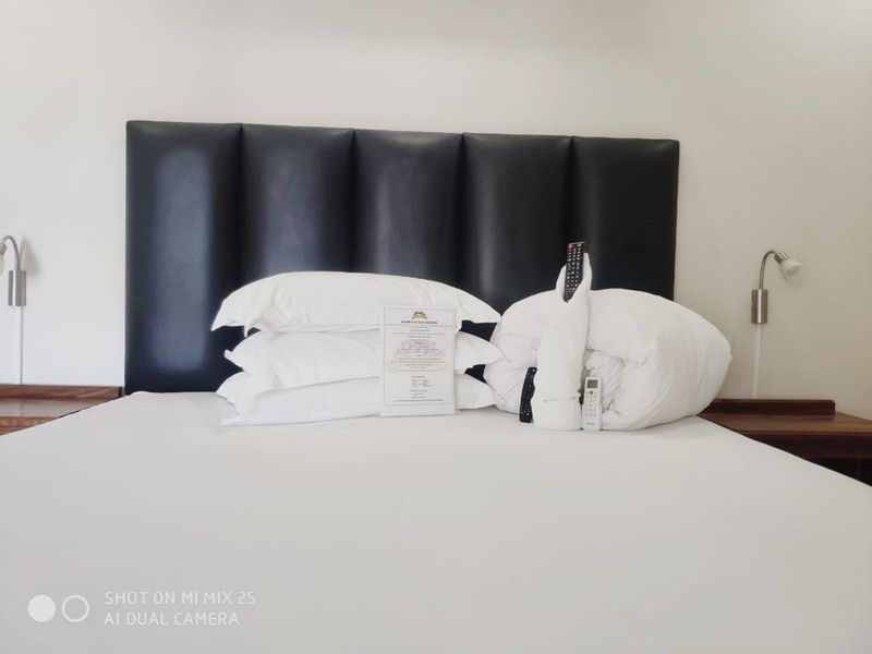 A bedroom featuring a dark upholstered headboard and integrated bedside shelving units.
