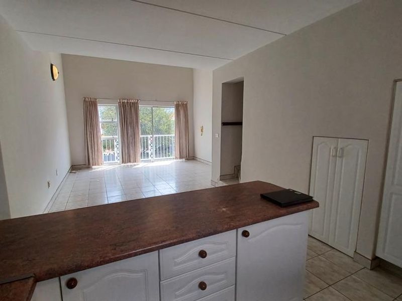 Spacious open-plan living area featuring a kitchen island, tiled flooring, and sliding glass doors leading to an outdoor space.