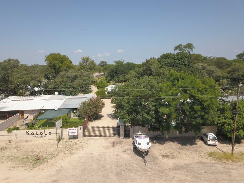 Aerial view of the Kololo Guest House property, featuring a gated entrance, gravel driveway, and established trees on the grounds.