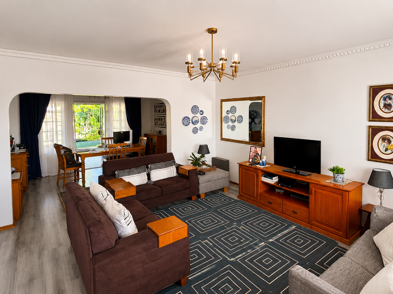 Spacious open-plan living and dining area featuring crown molding, laminate flooring, and an archway leading to a bright dining space with garden access.