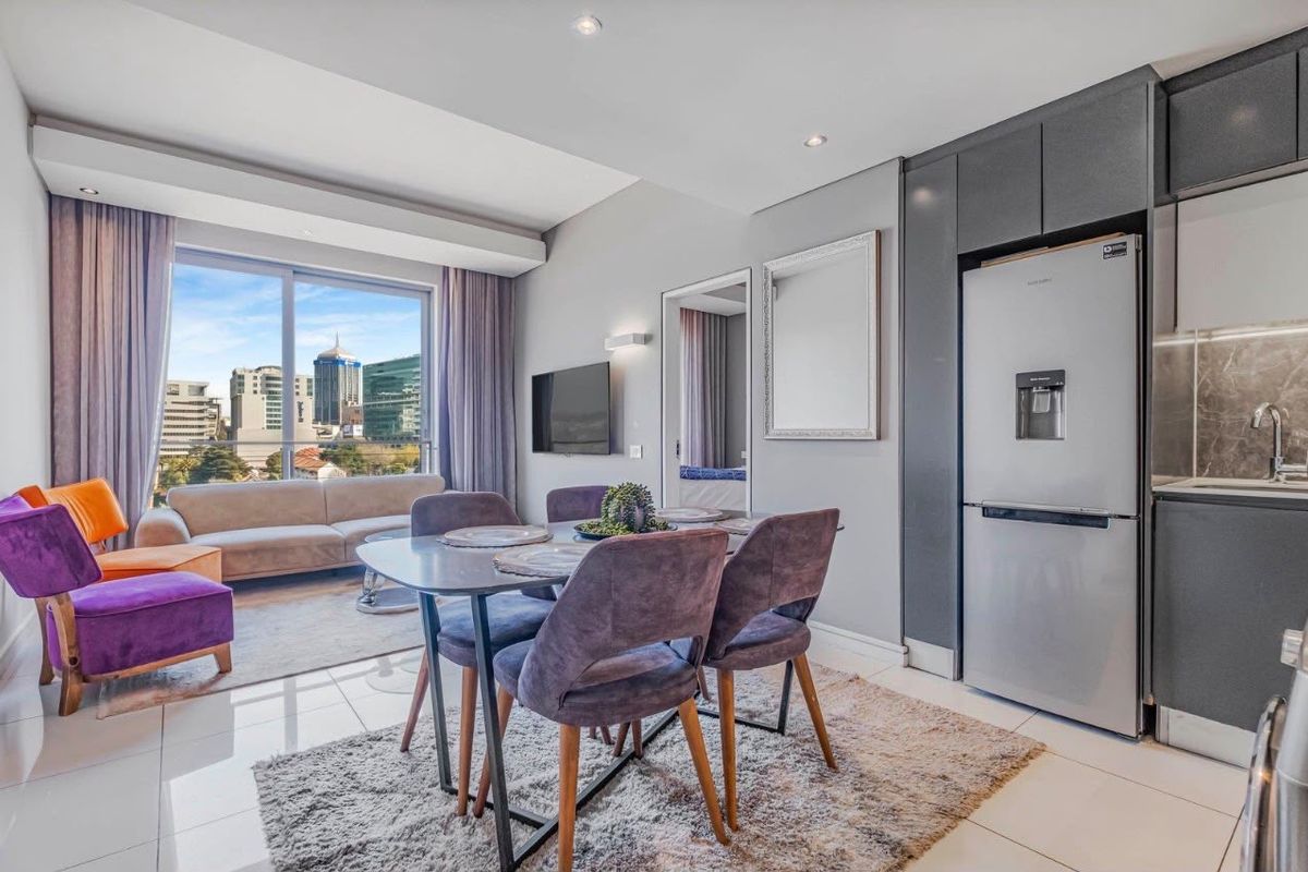 Modern open-plan living and kitchen area featuring sleek cabinetry, tiled floors, and large sliding doors with expansive city views.