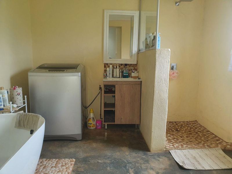 A functional bathroom featuring a freestanding bathtub, a vanity cabinet with mirror, and a walk-in shower with pebble tile flooring.