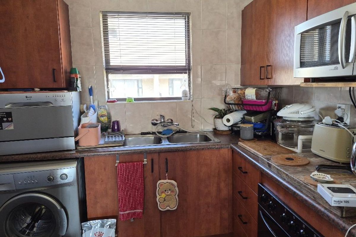 A functional kitchen featuring wooden cabinetry, laminate countertops, a double basin sink, and built-in appliances including an oven and microwave.