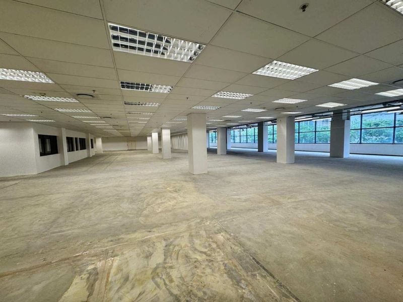 Expansive open-plan retail or office space featuring a suspended ceiling, recessed lighting, concrete flooring, and large windows providing ample natural light.