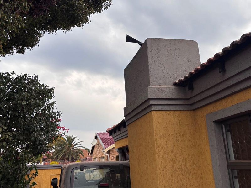 A view of the property exterior featuring a textured plaster facade, terracotta roof tiles, and a chimney stack.