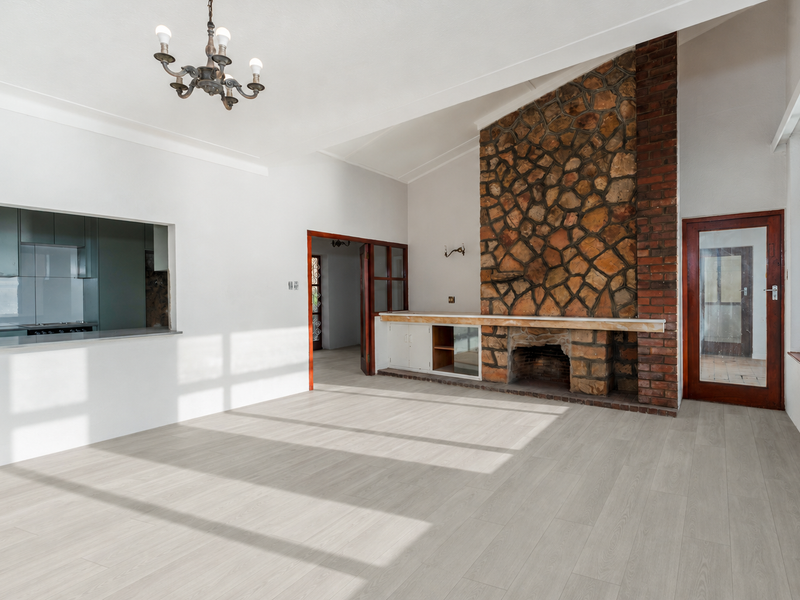 Spacious living room featuring a prominent stone fireplace, vaulted ceilings, and a convenient pass-through window connecting to the kitchen area.