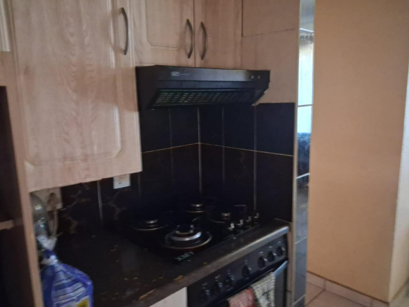 A functional kitchen area featuring built-in cabinetry, a gas hob, an integrated oven, and a dark tiled backsplash.