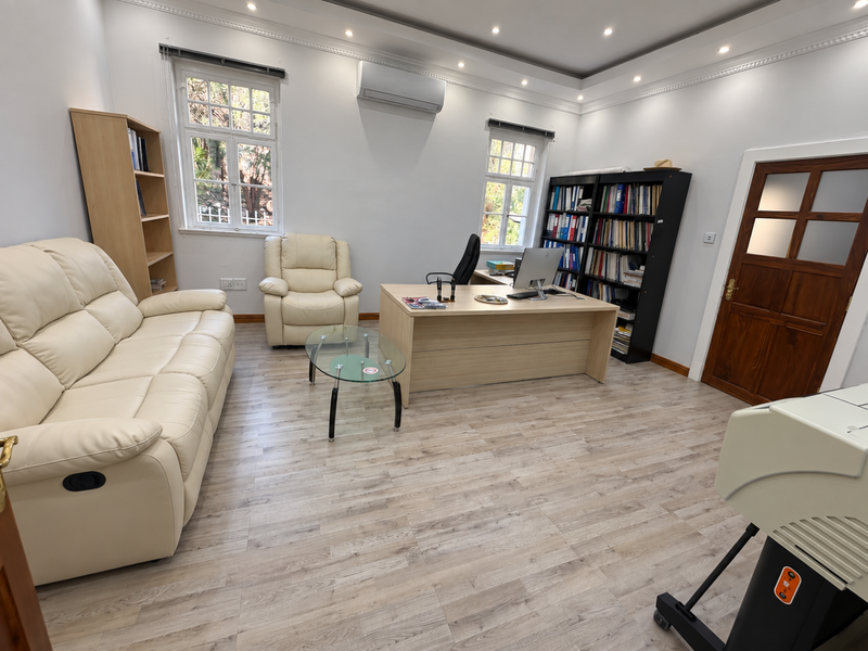 A well-maintained office space featuring laminate wood flooring, recessed ceiling lighting, crown molding, and a split-system air conditioning unit.