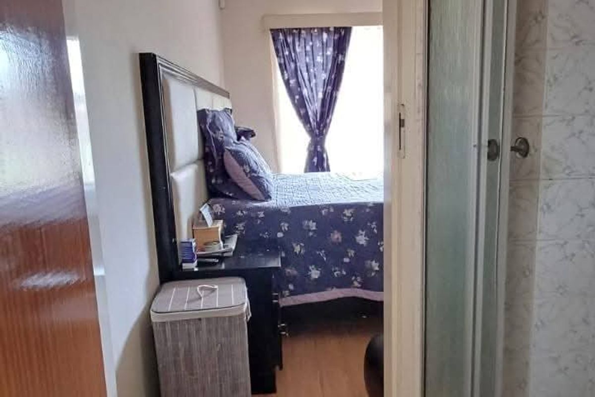 View from a bathroom doorway looking into a bedroom featuring tiled flooring and a wooden ceiling trim.