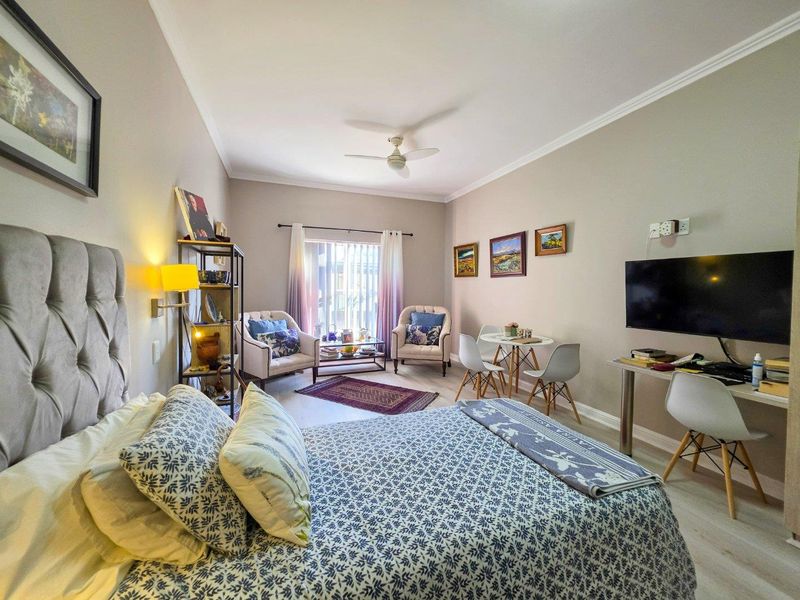 Spacious bedroom featuring laminate flooring, a ceiling fan, and a sliding glass door providing natural light and access to the exterior.