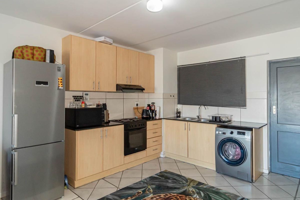 Functional kitchen featuring light wood cabinetry, dark countertops, integrated oven and hob, and dedicated space for a washing machine.