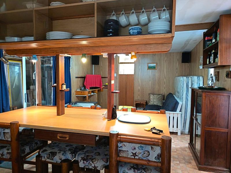 A dated kitchen area featuring extensive wood paneling, built-in wooden cabinetry, and a central breakfast bar with integrated storage.