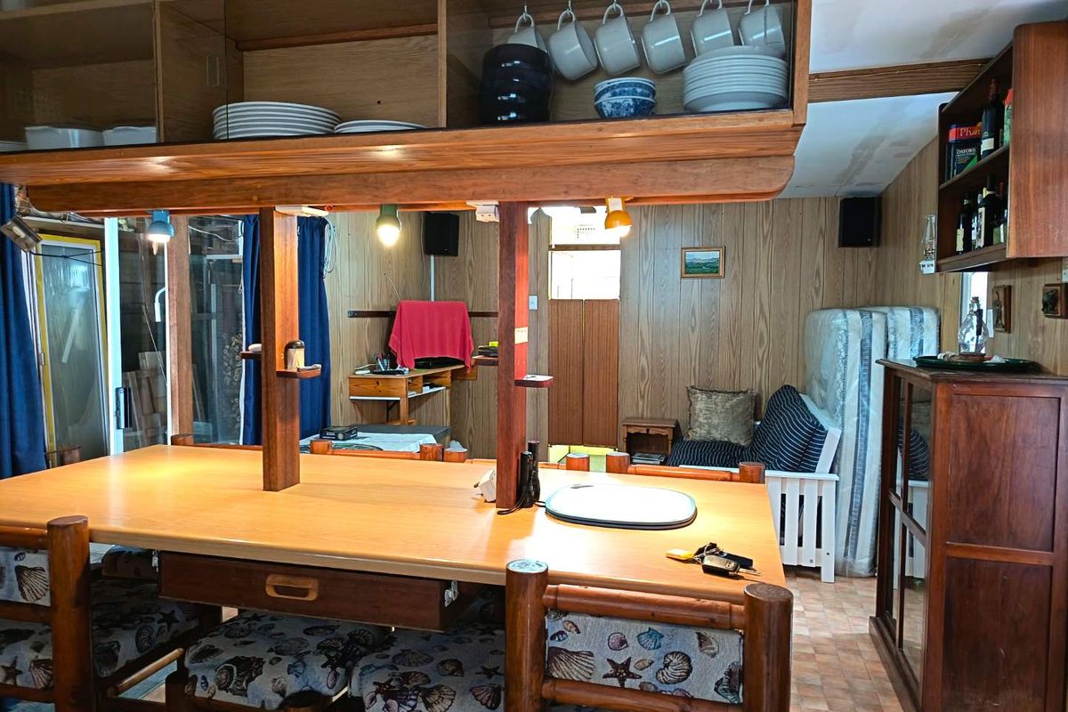 A dated kitchen area featuring extensive wood paneling, built-in wooden cabinetry, and a central breakfast bar with integrated storage.