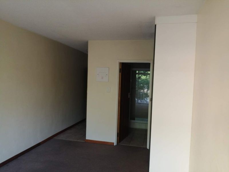An empty living area featuring a mix of carpet and tile flooring, with a doorway leading to an adjacent space.