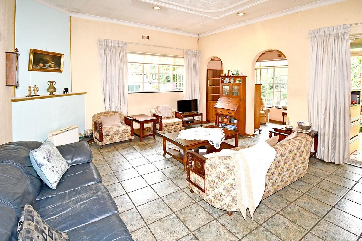 Spacious living room featuring tiled flooring, a fireplace, and arched doorways leading to an adjacent sunroom area.