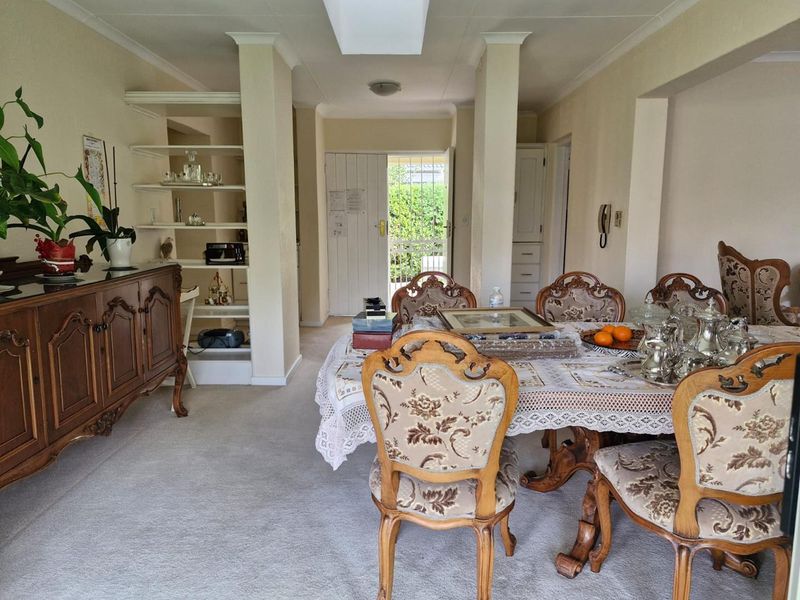 A dining room featuring built-in shelving, neutral wall finishes, and direct access to the exterior through a security gate.