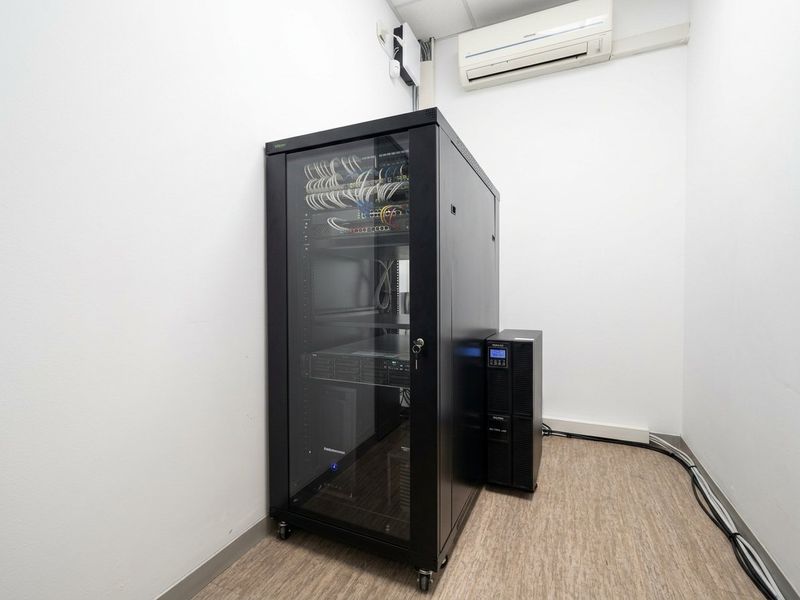 A dedicated server room featuring a secure network rack, UPS power backup, and wall-mounted climate control for optimal equipment performance.