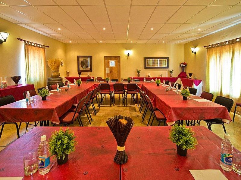 A spacious hotel function room or clubhouse area featuring a suspended ceiling, recessed lighting, and wall sconces, currently set up for a conference or event.
