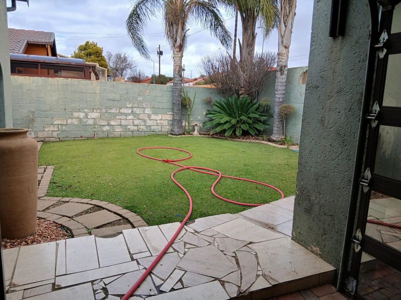 A private rear garden featuring a lawn area, paved patio section, and perimeter boundary walls.