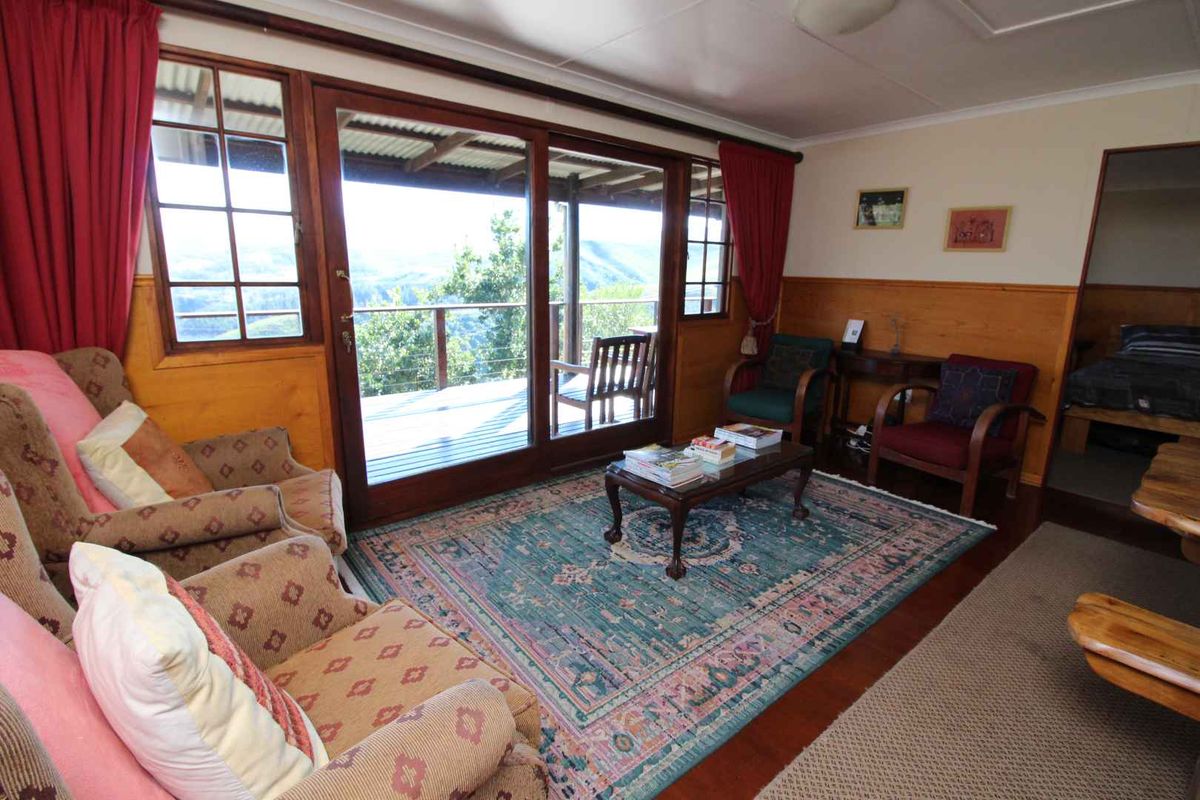 A cozy living room featuring timber wall paneling, large sliding glass doors, and direct access to an outdoor deck with scenic views.