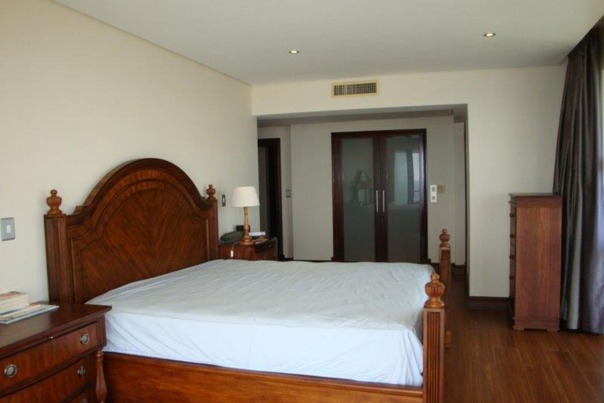 Spacious bedroom featuring warm timber flooring, recessed downlighting, and integrated air conditioning vents, leading to a private en-suite bathroom with frosted glass doors.