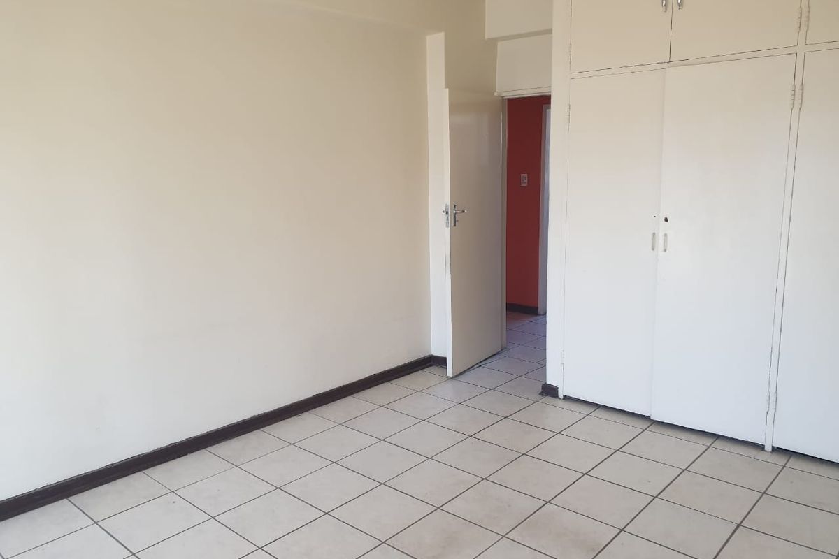 A vacant bedroom featuring built-in cupboards and tiled flooring, offering a clean and neutral space ready for personalization.