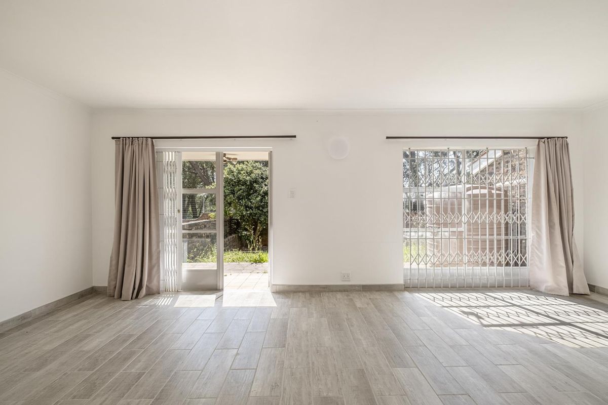Bright and spacious living area featuring modern wood-look tile flooring, security gates, and direct access to the outdoor garden area.