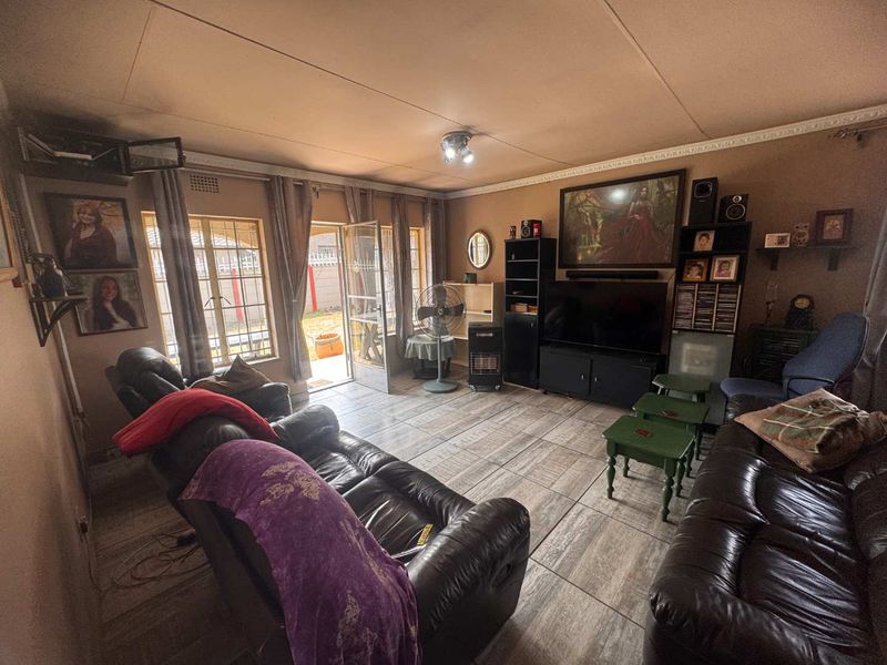 A living room featuring tiled flooring, ceiling cornice detailing, and direct access to the exterior through a security gate.