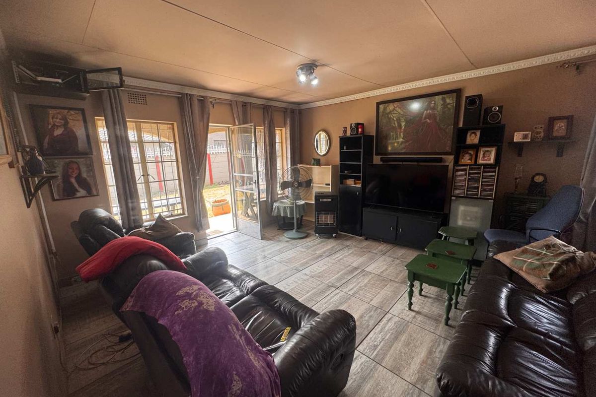 A living room featuring tiled flooring, ceiling cornice detailing, and direct access to the exterior through a security gate.
