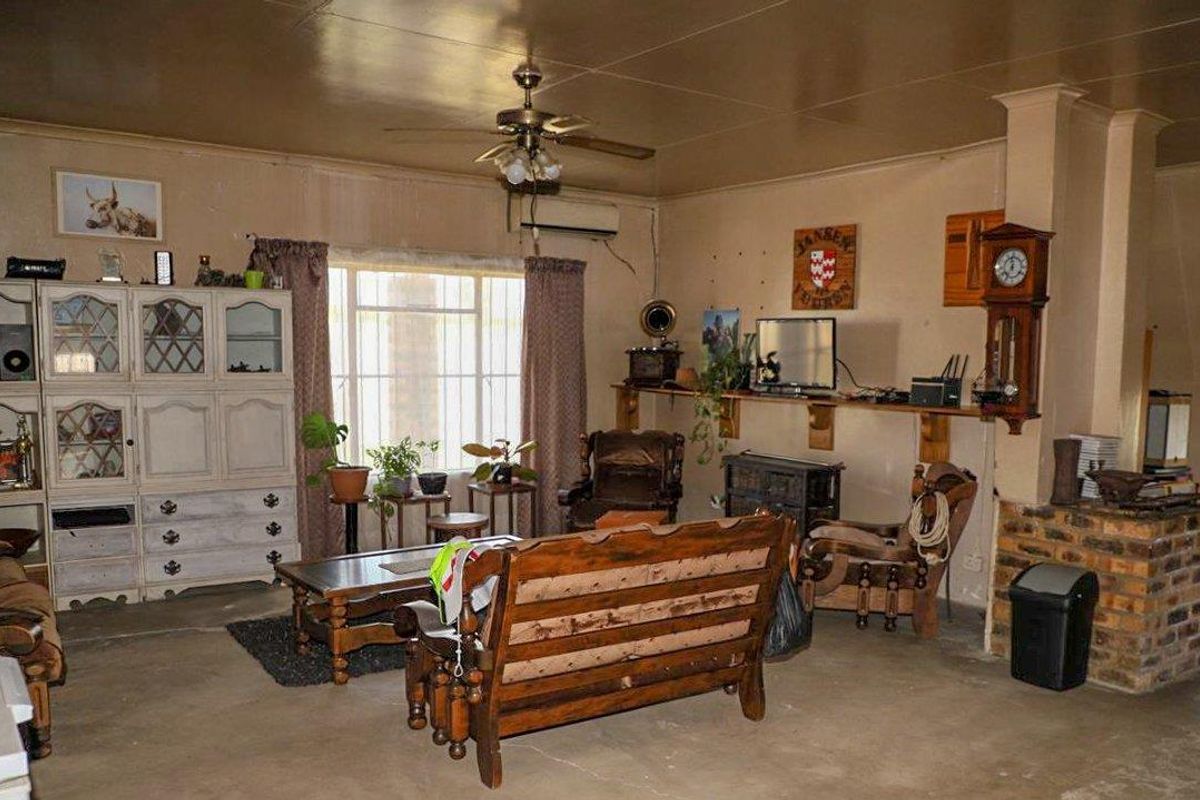 Spacious living area featuring a brick fireplace, ceiling fan, and air conditioning unit, offering a rustic and functional layout.