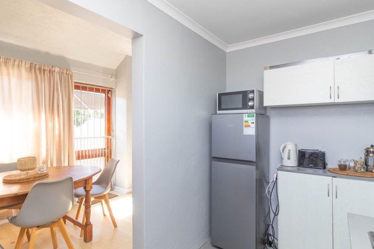 A compact kitchen area featuring built-in cabinetry and a microwave, with an adjacent dining space visible through the doorway.