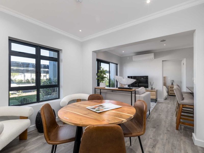 Modern open-plan living and dining area featuring laminate flooring, recessed lighting, and a split-system air conditioner, creating a bright and cohesive living space.