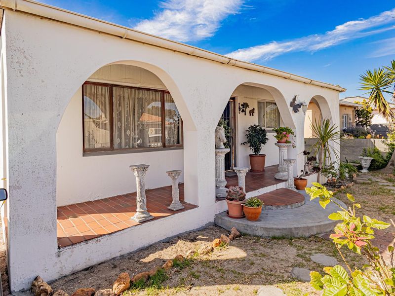 Front elevation of a house featuring a covered veranda with distinctive arched architectural details and terracotta tiling.