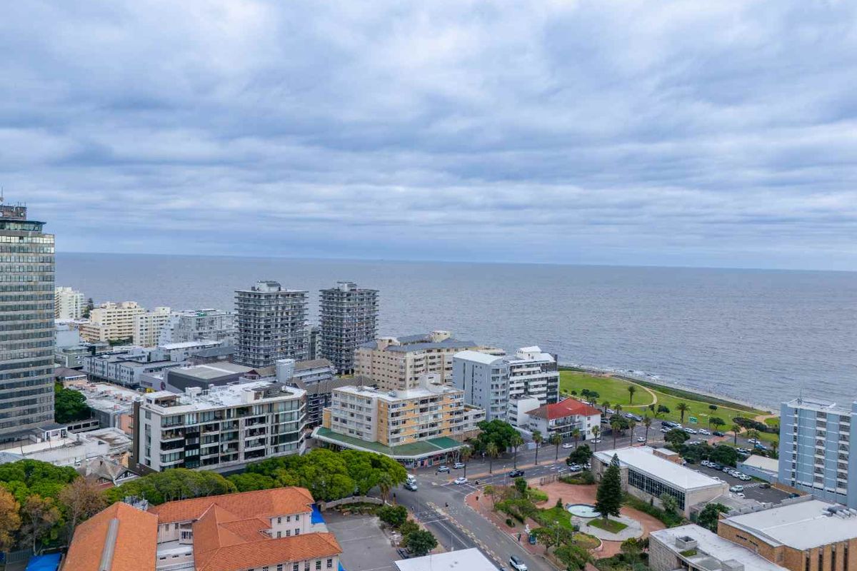 Elevated aerial view overlooking the coastal urban landscape, featuring proximity to the ocean, local streets, and surrounding apartment buildings.