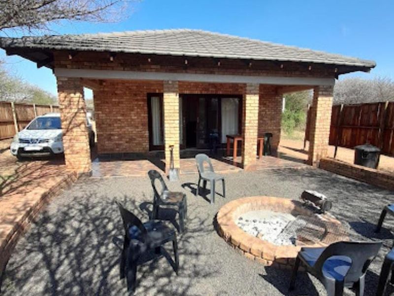 A covered brick patio area featuring a built-in circular fire pit and tiled flooring, providing an outdoor entertainment space.