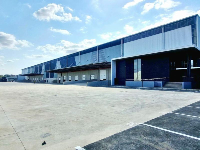 Modern industrial warehouse facility featuring extensive concrete yard space, multiple loading docks with roller shutter doors, and high-quality metal cladding exterior.