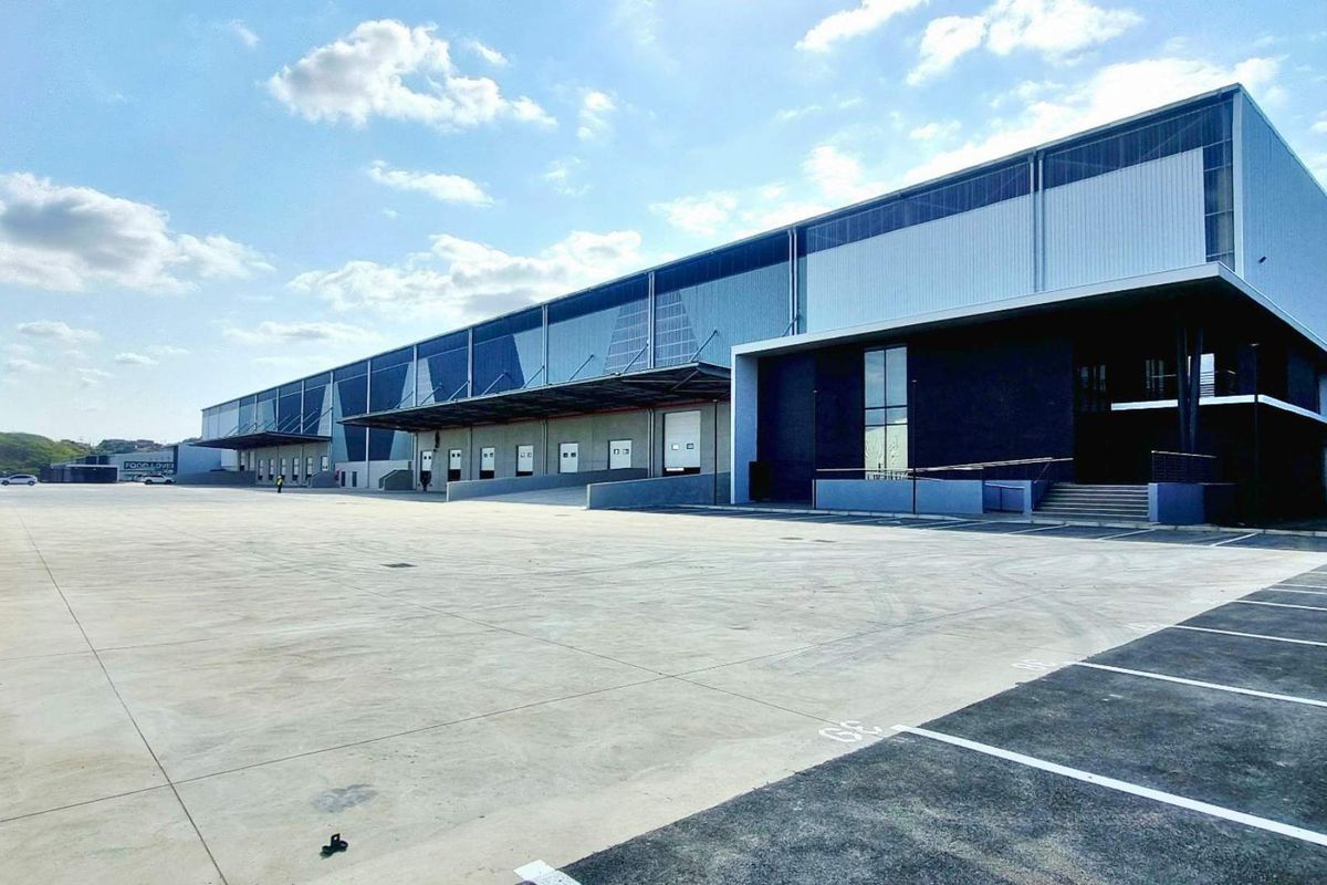 Modern industrial warehouse facility featuring extensive concrete yard space, multiple loading docks with roller shutter doors, and high-quality metal cladding exterior.