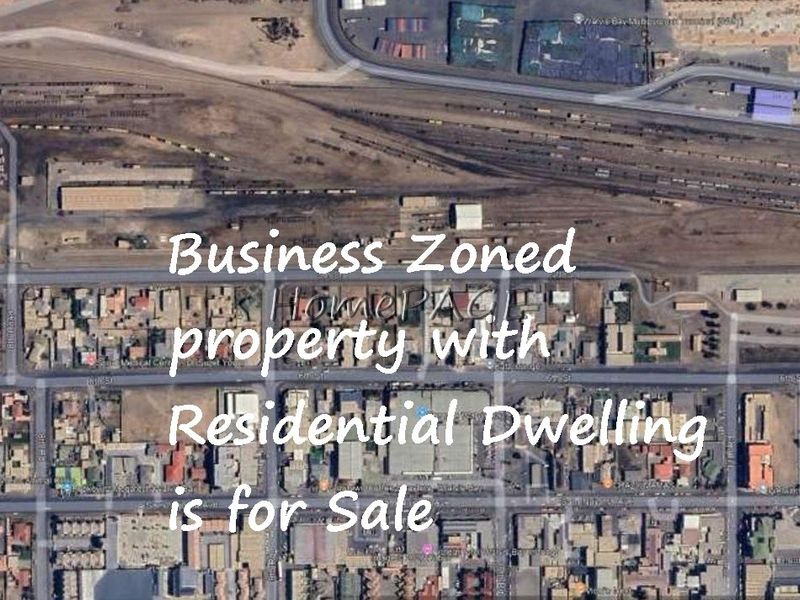An aerial view of a commercial business-zoned property featuring a residential dwelling, situated in an urban area.