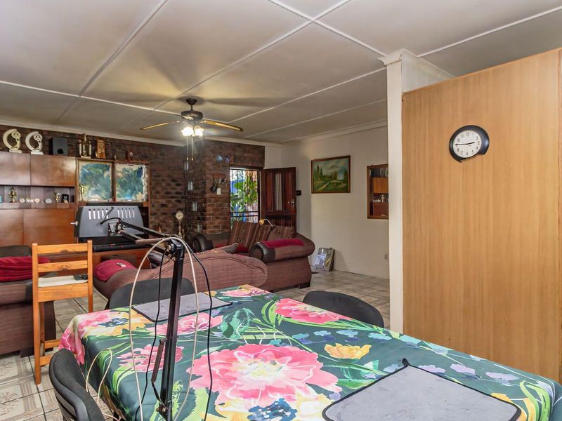Open plan living and dining area featuring exposed brickwork, tiled flooring, and a ceiling fan, offering a functional layout with potential for modernization.