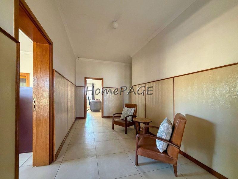 A spacious hallway featuring tiled flooring and timber wall paneling, providing a neutral transition space between rooms.