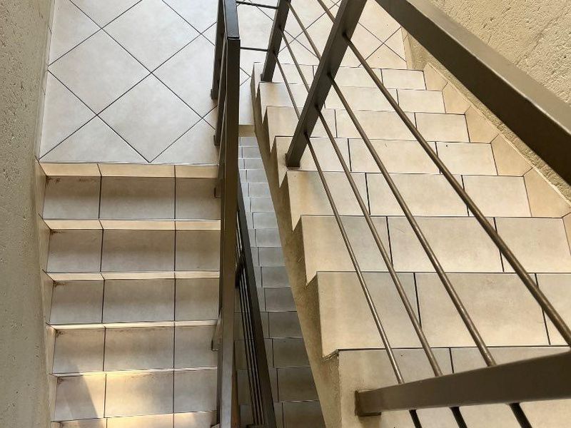 A functional stairwell featuring tiled steps and a sturdy metal balustrade, providing access between levels in the apartment complex.