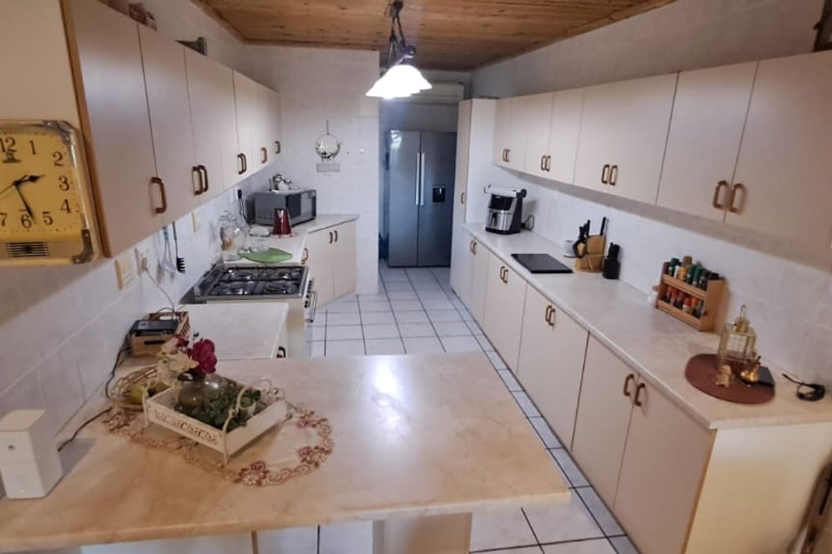 A functional galley-style kitchen featuring extensive built-in cabinetry, tiled flooring, and a breakfast counter, providing ample storage and workspace.