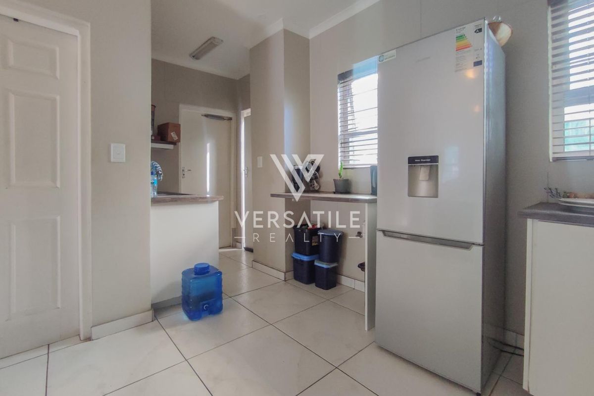 A functional kitchen area featuring tiled flooring, built-in cabinetry, and a breakfast counter, providing a practical space for daily meal preparation.