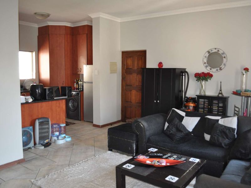 Open plan living area featuring tiled flooring, coving, and a kitchen with built-in cabinetry and granite countertops.